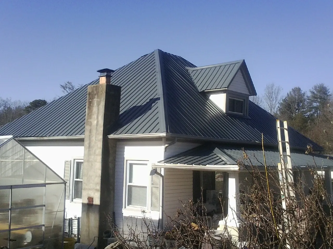 Dark blue standing seam metal roof on a white farmhouse with dormer — Slate & Tile Roof Repair by Roofing Brothers in Corydon