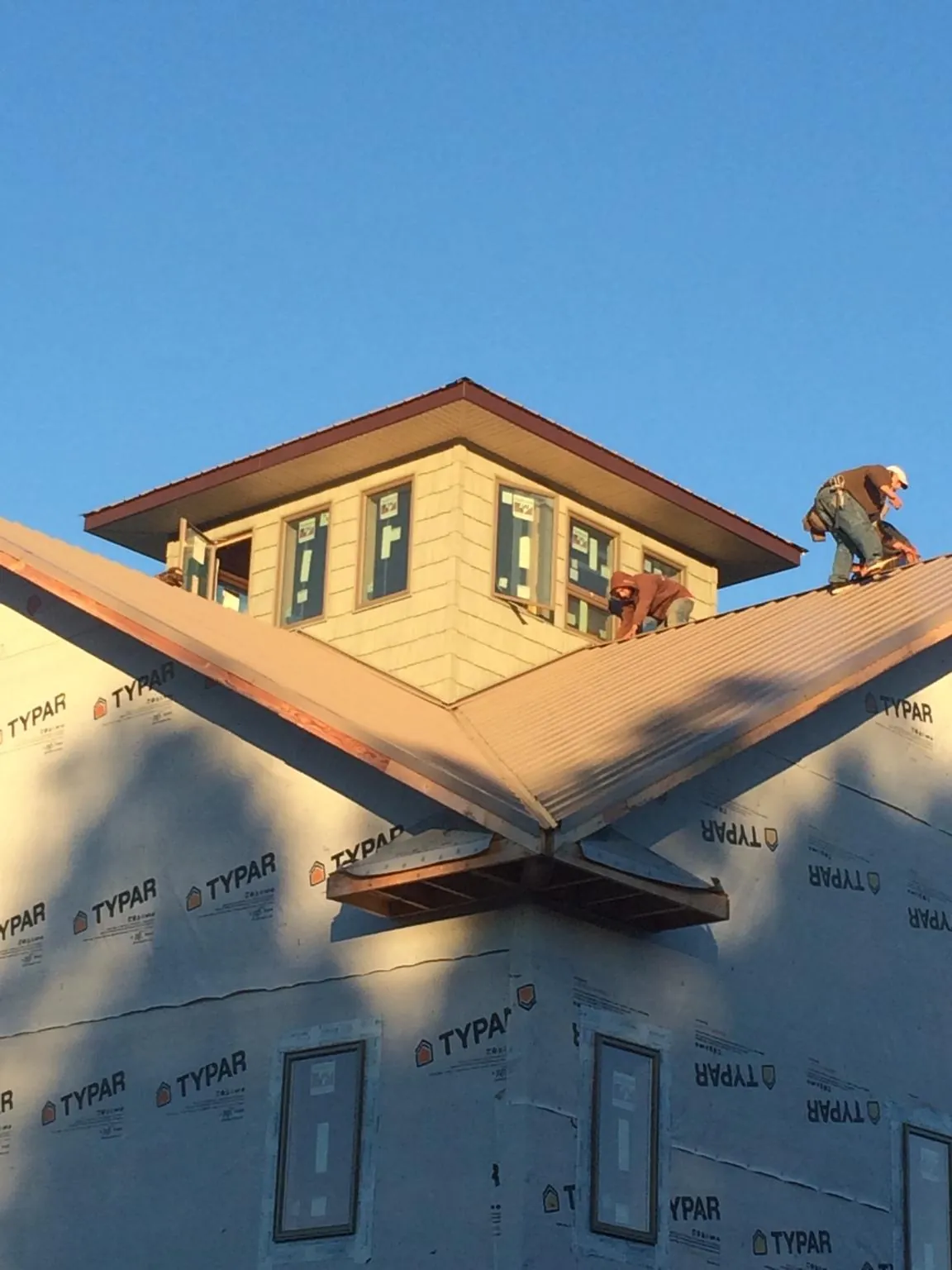 Roofers working around a rooftop cupola on a new metal roof at sunset — Roof Waterproofing in Corydon by Roofing Brothers